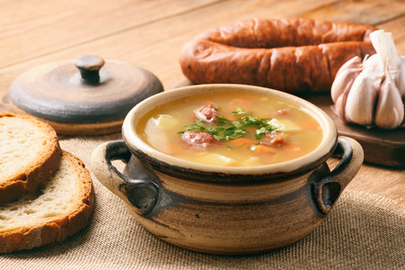 Pea soup with smoked sausage on brown wooden background.の写真素材