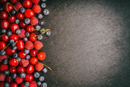 Summer berries (blueberries, raspberries and cherries) on black background.の写真素材