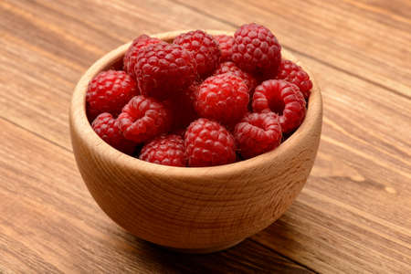 Ripe raspberries in wooden bowl. Close-up.の写真素材