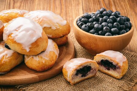 Sweet yeast buns with blueberries on brown wooden table.の写真素材