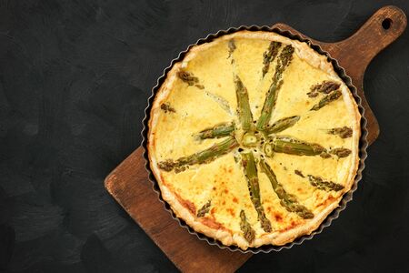 Homemade tart with asparagus and cheese on black background.の写真素材