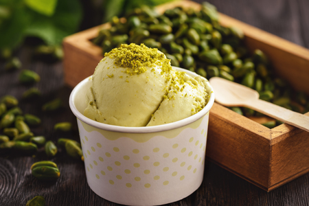 Pistachio ice cream in a paper cup on a dark wooden background.の写真素材