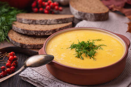 Pumpkin soup in a ceramic bowl on a wooden background.の写真素材