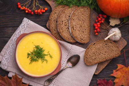 Pumpkin soup with dill and bread on a wooden backgroundの写真素材