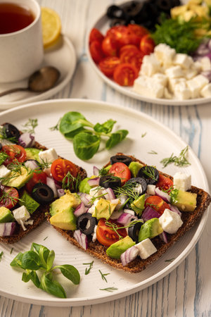 Tasty and healthy avocado, olives, cherry tomatoes and feta cheese sandwiches. Toasts with avocado, tomatoes and feta cheese.の写真素材