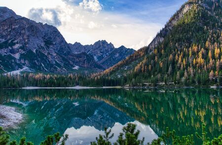 The calm waters of Lake Braies reflect the woods and mountains on a beautiful autumn day. HDR imageの写真素材
