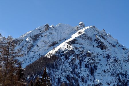 The snow-covered peak of the mountains is illuminated by the rays of the sun
