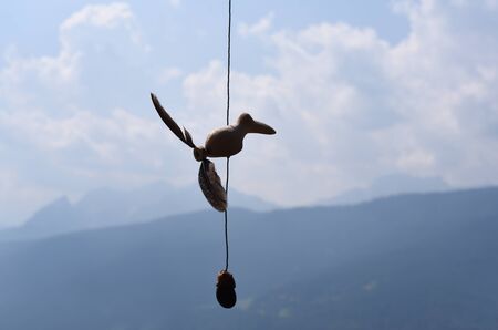 A small wooden toy hung to challenge the wind against the backdrop of the mountainsの写真素材