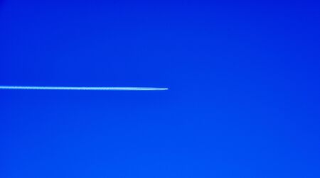 An airliner flies to its destination in an immense blue skyの写真素材
