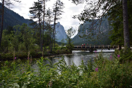 Small wooden bridge over the Rienza river leaving the Dobbiaco lakeの写真素材