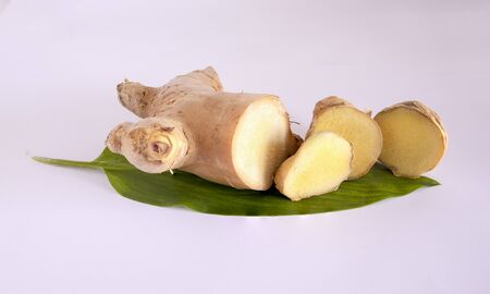 Ginger root and slices with leaves isolated on white backgroundの写真素材