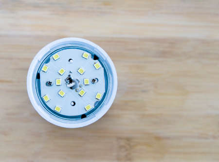 Open LED light bulb on a wooden background. The concept of how to saving energy. Flat lay.