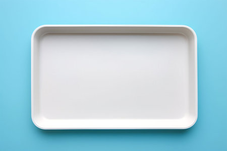 Empty white tray isolated on blue background. Top view. Flat lay.の素材