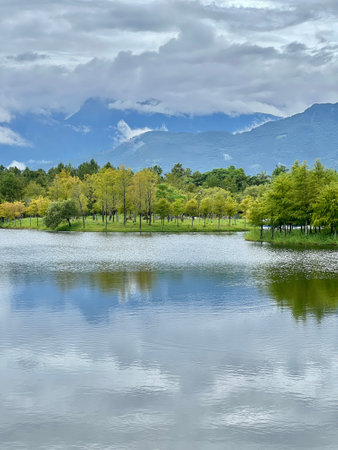 Lake and forest on the background of mountains and blue sky with cloudsの写真素材