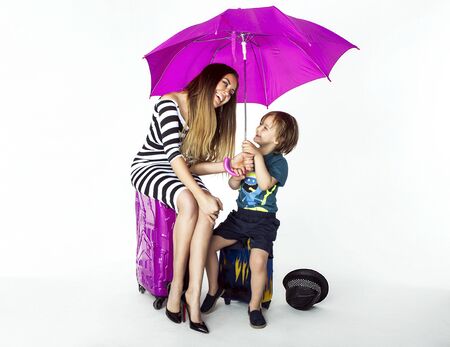 Smiling fashionable mother posing with young son in studio. Two travelers.の写真素材