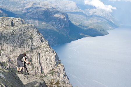 man filming norwegian fjordの写真素材