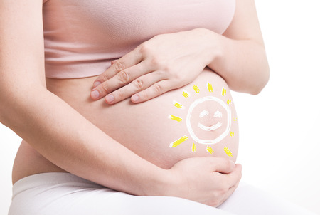 pregnant woman with hands over tummy at white backgroundの写真素材