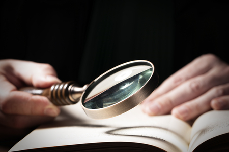 Criminal or tax investigation concept. Hand with detective magnifying glassの写真素材