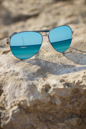 reflected in the glasses blue sea and yachton on beach background close upの写真素材