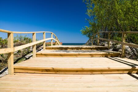 Wooden pier close to sunny beach and blue skyの写真素材