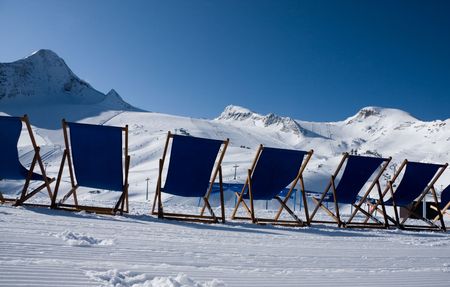 Deckchairs in front of ski slopes in alpsの写真素材