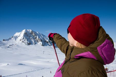 Woman in ski clothes pointing hill in alps mountains