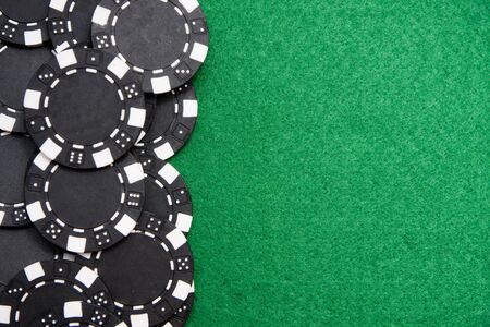 Black gambling chips on green felt background with copy spaceの写真素材
