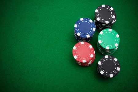 Five stacks of gambling chips on green felt backgroung