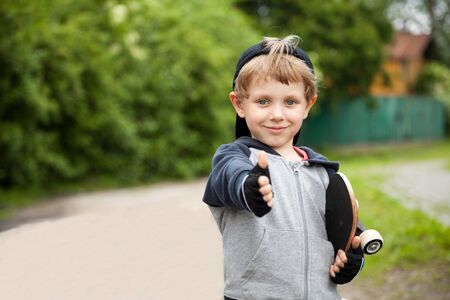  	Boy with skateboard showing thumbs up sign outdoorsの写真素材