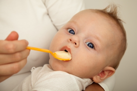 Mother feeding her 4 month old son with spoonの写真素材