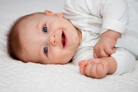 10 months old boy laying on bad amd smiling