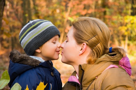 Mother kissing her 3 years old son in autumn scenery の写真素材