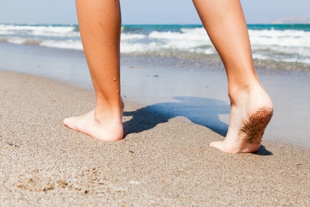 Woman walking barefoot on sunny beach in summer dayの写真素材