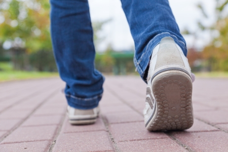 Teenager walking in sport shoes on pavement in autumn day Teenager walking in sport shoes on pavement in autumn day