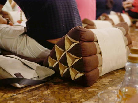 A man, tourist, sitting and resting on a triangle pillow during his traditional Northern Thai  (Khantok) dinner in Chiang Mai, Thailandの写真素材