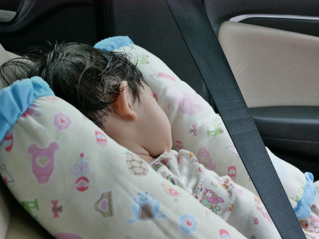 Little Asian baby sleeping in a driving car without a proper baby carseatの写真素材