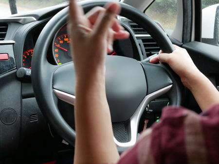 Selective focus of woman hand on steering wheel driving a car with one hand