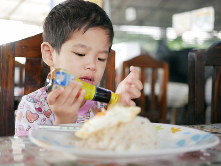 Little Asian baby learning to close the lid of soy bean sauce bottle by herself - child development by learning to do things by themselvesの写真素材