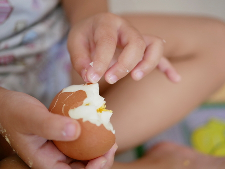 Close up of Asian baby's fingers peeling boiled egg by herself