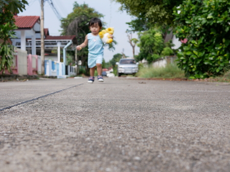 Concrete road in the compound where little Asian baby girl, in the background, is using as a playground and a place to learn how to walkの写真素材