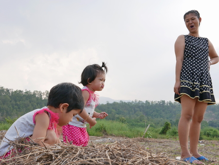 Asian mother and her two little baby girls enjoys spending time outdoor together on the weekends at an open fieldの写真素材