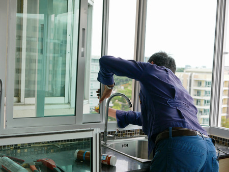 Asian technician installing a sliding window for high rise apartment buildingの写真素材