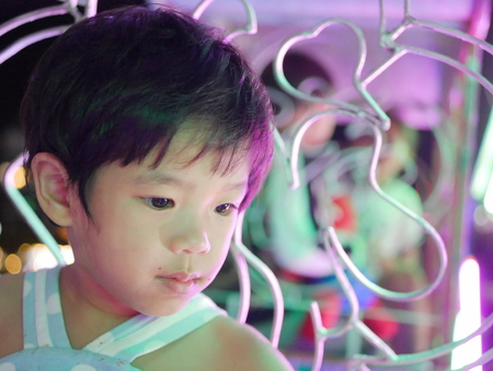 Close up of little Asian baby girl on a ferris wheel at nightの写真素材