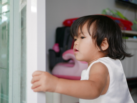 Little Asian baby girl, 20 months old, learning to pull / close a sliding door by herselfの写真素材