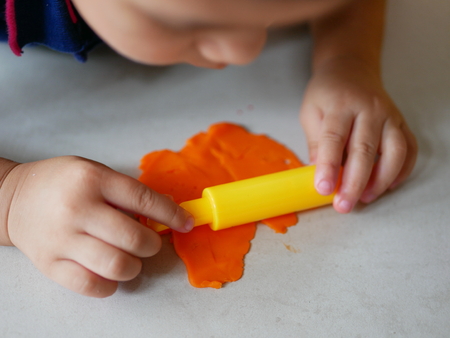Close up of little baby's hands rolling playdough on the house floorの写真素材