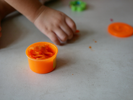 Little baby's hands collecting and putting playdough back into the box, after finish playingの写真素材