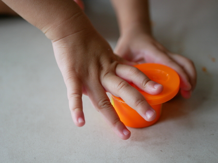 Little baby's hands collecting and putting playdough back into the box, after finish playingの写真素材