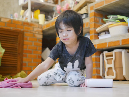 Little Asian baby girl cleaning her own mess, body powder, on the house floor - allowing baby to clean up their own mess to develop their sense of responsibilityの写真素材