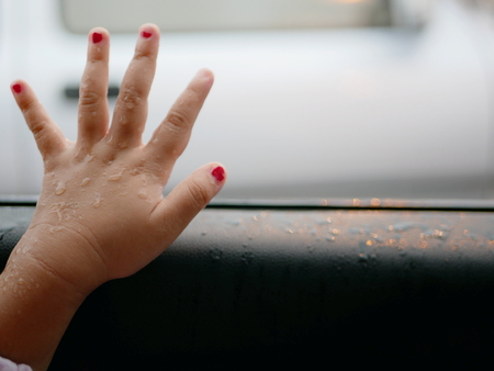 Little baby's hand placed next to the opened window of a car to let the rain falling onto - baby's curiosityの写真素材