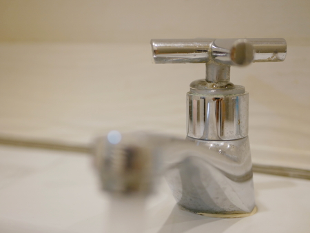 Selective focus of water coming out from a leaky opened water tap / faucet around its valveの写真素材